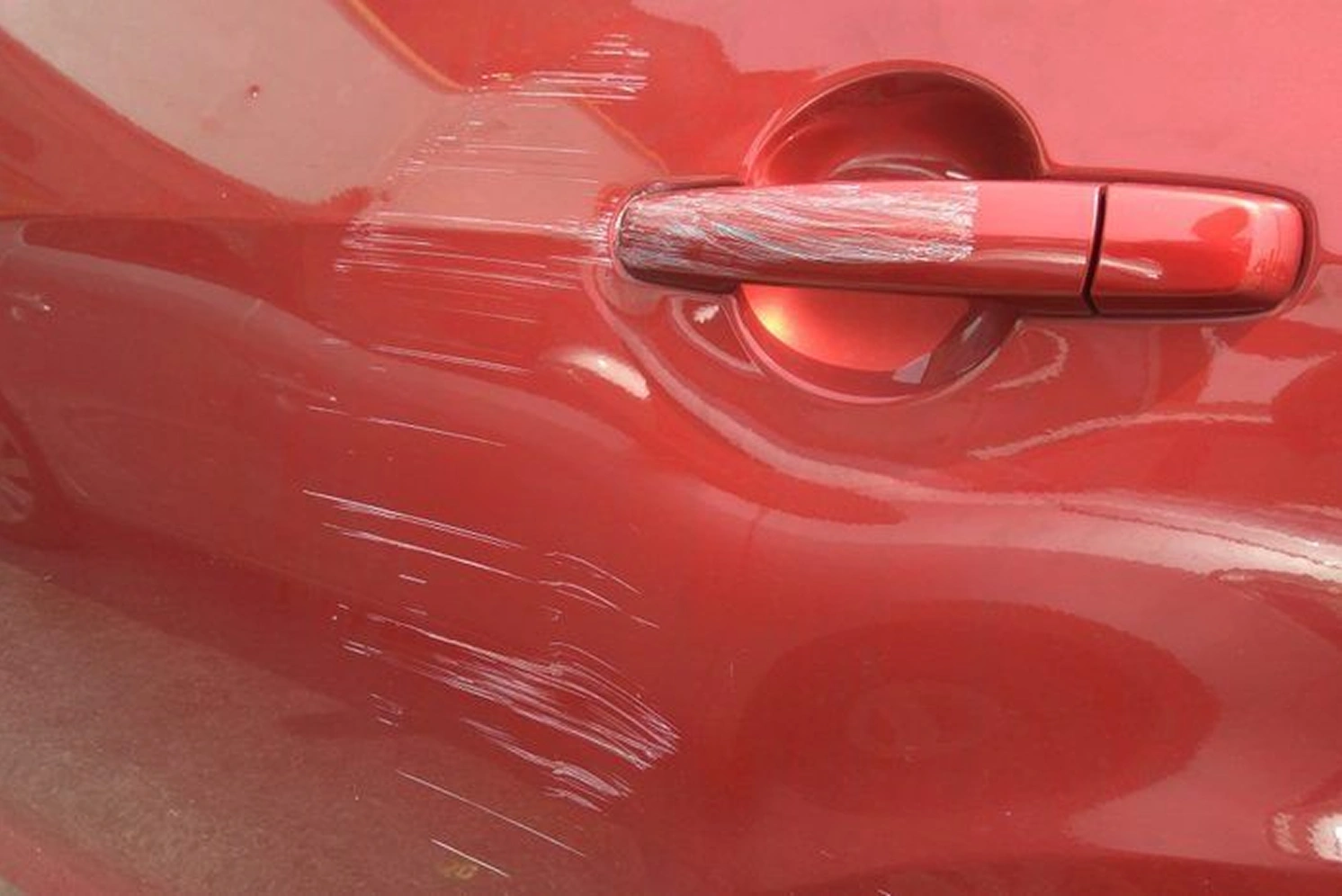 Une image montrant une voiture rouge sur la quelle il y a des griffes.